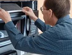 Appliance repair technician replacing a microwave vent filter in Birmingham, AL