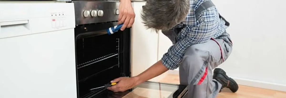 Oven repair technician inspecting and servicing an electric oven in Birmingham, AL