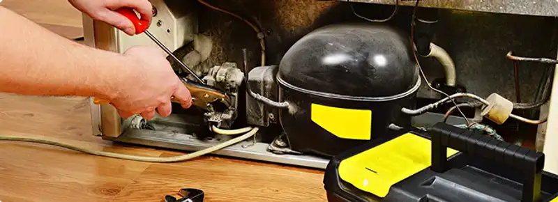 Refrigerator repair technician fixing the compressor and wiring in Birmingham, AL